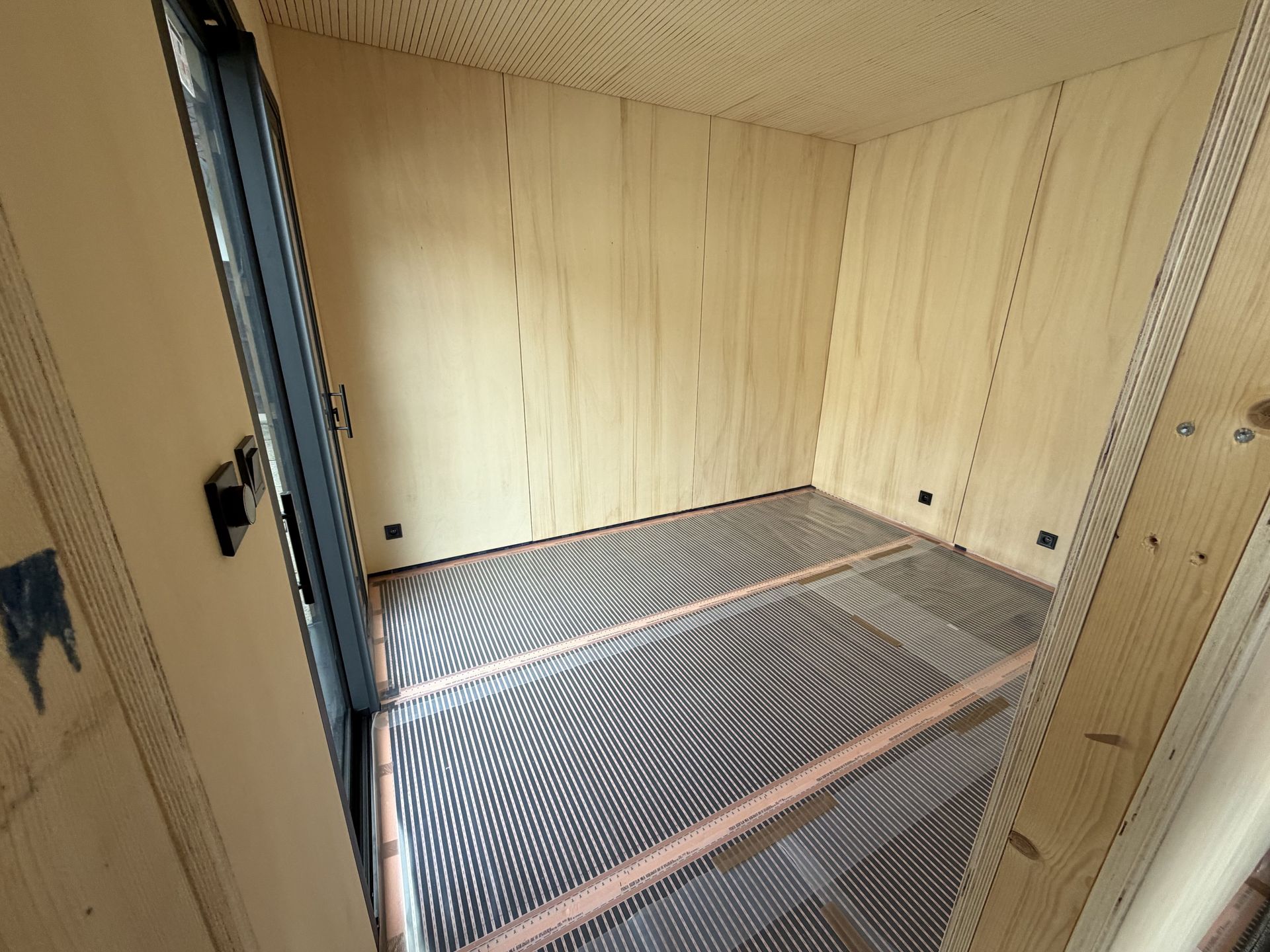 Instalace elektrického podlahového vytápění pomocí topných fólií v moderní dřevostavbě.