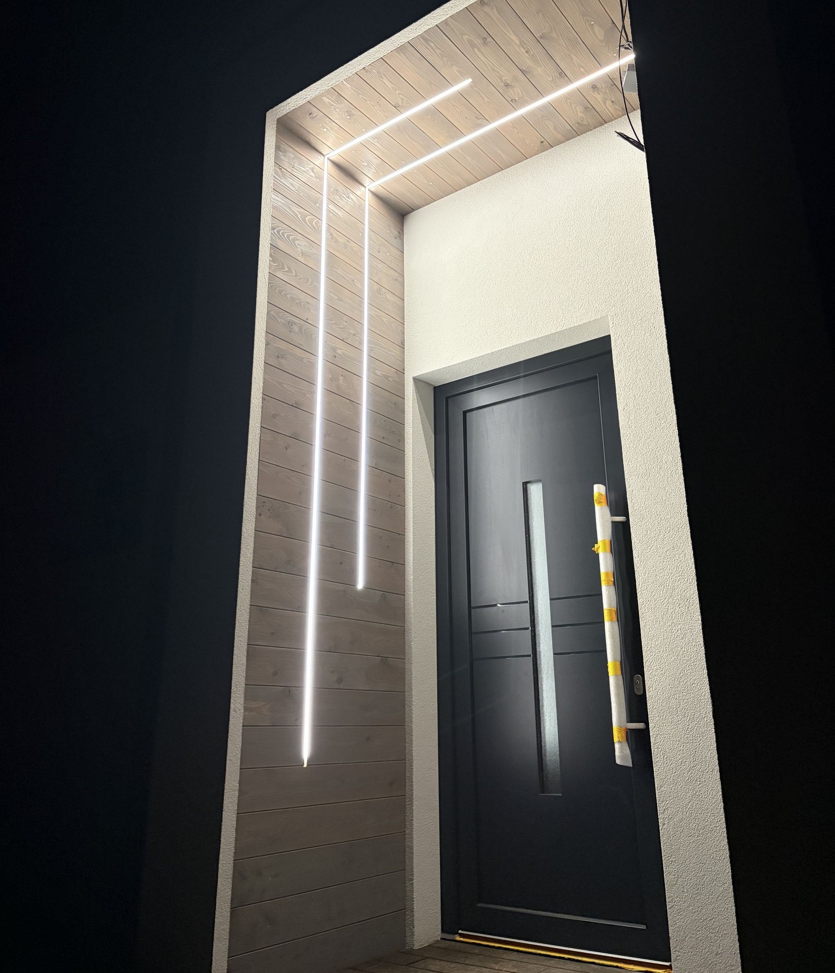 Montáž venkovního designového LED osvětlení zapuštěného do obložení u vstupu do rodinného domu.